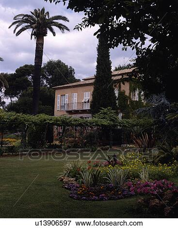 Flowerbeds in lawn in front of house in southern France with tall palm trees View Large Photo Image Stock Photo - Flowerbeds in lawn in front of house in southern France with tall palm trees. Fotosearch