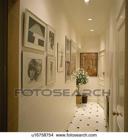 Framed black+white photographs in narrow white hall with tiled floor and recessed ceiling spotlights View Large Photo Image Picture - Framed black+white photographs in narrow white hall with tiled floor and recessed ceiling spotlights. Fotosearch