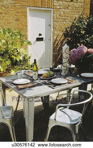 Stock Image - Furniture on patio in country garden in summer. Fotosearch