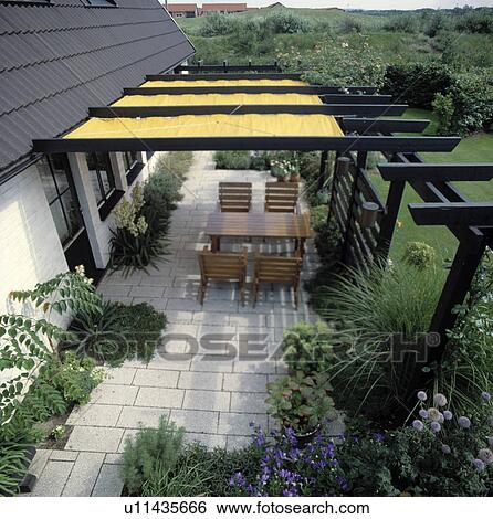 Stock Photograph - Furniture on patio in country garden in summer. Fotosearch