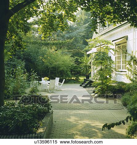 Stock Photography - Furniture on patio in country garden in summer. Fotosearch