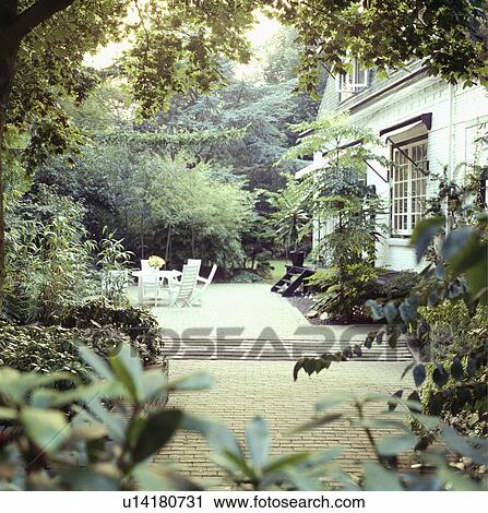 Furniture on patio in summer garden in front of country house View Large Photo Image Stock Image - Furniture on patio in summer garden in front of country house. Fotosearch