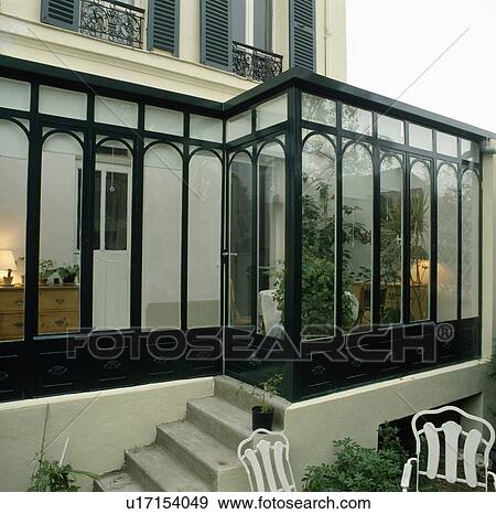 Stock Photo - Glass conservatory extension on traditional town house in France. Fotosearch