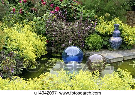 Stock Photo - Glass globes and small pond in country garden. Fotosearch