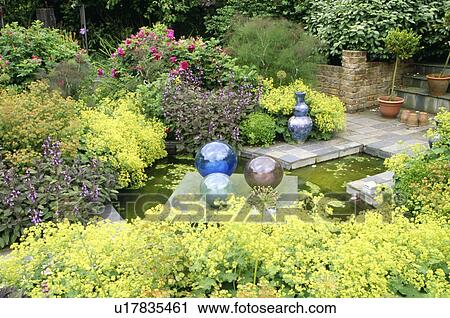 Stock Image - Glass globes and small pond surrounded by Alchemilla Mollis. Fotosearch