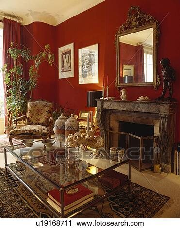 Stock Image - Glass-topped table in traditional red living room. Fotosearch
