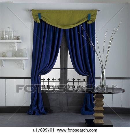 Stock Image - Green and blue swagged curtains in living room. Fotosearch