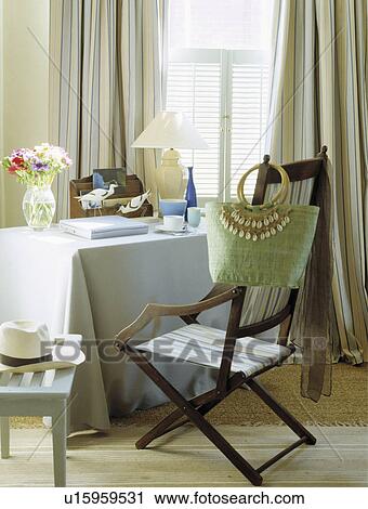Green bag on old campaign chair beside table with pastel blue cloth in coastal dining room View Large Photo Image Stock Image - Green bag on old campaign chair beside table with pastel blue cloth in coastal dining room. Fotosearch