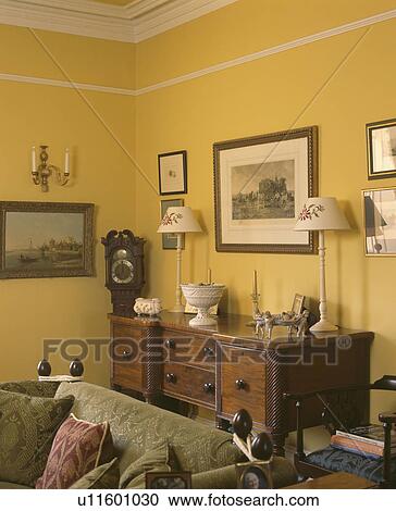 Stock Image - Green velour sofa in front of sideboard in yellow livingroom. Fotosearch