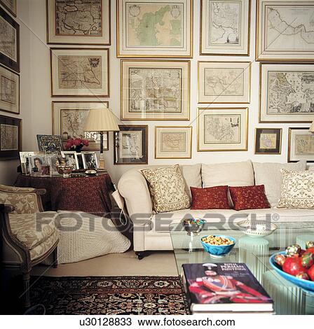 Stock Image - Group of pictures on wall above sofa in traditional living room. Fotosearch