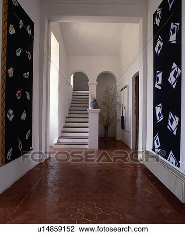Hexagonal terracotta tiles on floor of white traditional country hall with large black+white abstract pictures View Large Photo Image Stock Image - Hexagonal terracotta tiles on floor of white traditional country hall with large black+white abstract pictures. Fotosearch