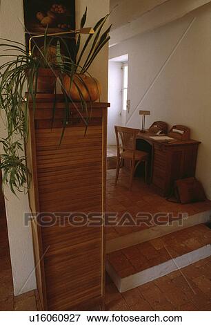 Houseplant on tall narrow wooden cabinet in white hall with small steps and terracotta tiled floor View Large Photo Image Stock Photo - Houseplant on tall narrow wooden cabinet in white hall with small steps and terracotta tiled floor. Fotosearch