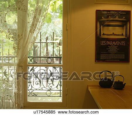 Japanese teapots below poster on wall beside French windows with white lace curtain View Large Photo Image Stock Photography - Japanese teapots below poster on wall beside French windows with white lace curtain. Fotosearch