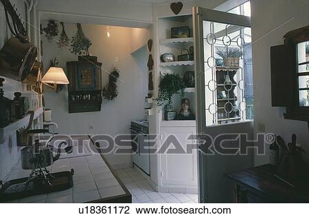 Stock Image - Kettle on white-tiled worktop in small white kitchen with half-glazed door. Fotosearch