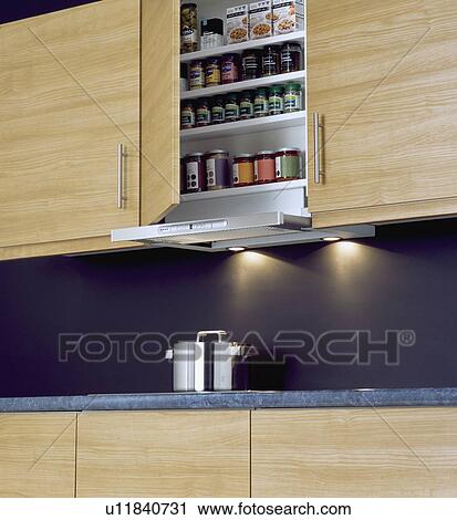 Kitchen cupboard door open to show jars on shelves above recessed lighting View Large Photo Image Stock Image - Kitchen cupboard door open to show jars on shelves above recessed lighting . Fotosearch