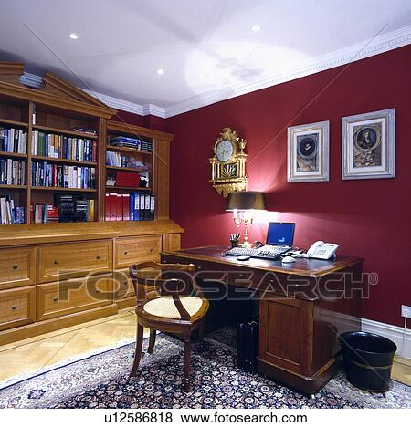 Laptop on traditional mahogany desk and chair in red study with pine bookcase View Large Photo Image Stock Photo - Laptop on traditional mahogany desk and chair in red study with pine bookcase. Fotosearch