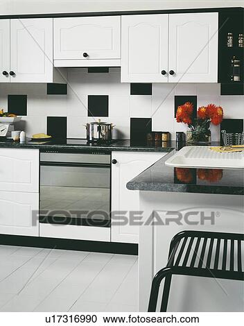 Large Black White Tiles On Wall Above Oven In Modern White Kitchen