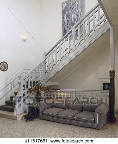 Large grey sofa and pale grey wooden staircase in hall with terrazo floor View Large Photo Image Stock Image - Large grey sofa and pale grey wooden staircase in hall with terrazo floor. Fotosearch