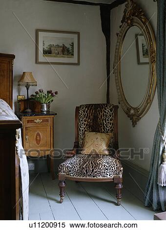 Large ornate gilt mirror on wall above faux leopardskin upholstered Victorian chair View Large Photo Image Stock Photography - Large ornate gilt mirror on wall above faux leopardskin upholstered Victorian chair. Fotosearch