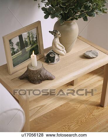 Stock Photo - Lighted candle and photograph with sculpture on small pale wood table. Fotosearch