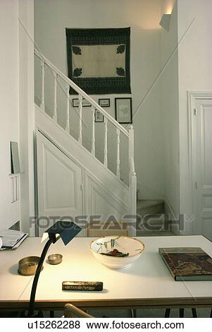 Lighted lamp on table in in small white hall study with picture above staircase View Large Photo Image Stock Photo - Lighted lamp on table in in small white hall study with picture above staircase. Fotosearch