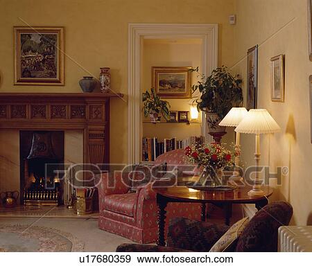 Lighted lamps and red armchair in traditional living room View Large Photo Image Stock Photo - Lighted lamps and red armchair in traditional living room. Fotosearch