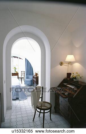 Lighted wall-lamp above antique desk and bentwood chair on landing beside arched door to bedroom View Large Photo Image Stock Photography - Lighted wall-lamp above antique desk and bentwood chair on landing beside arched door to bedroom. Fotosearch