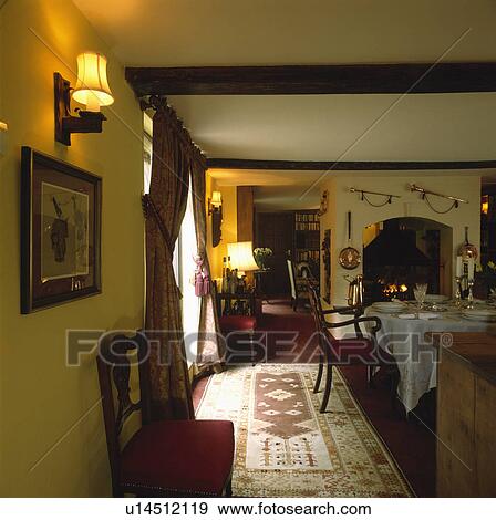 Stock Photo - Lighted wall lights and lamps in country dining room with patterned rug on carpet. Fotosearch