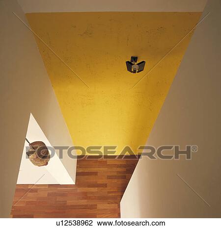 Stock Image - Looking down on modern hall with roughly plastered yellow wall and wooden flooring. Fotosearch