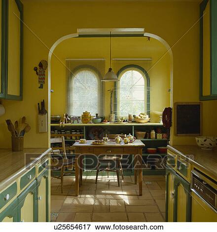 Looking through arch of yellow kitchen to wooden table and chairs in dining area View Large Photo Image Stock Photo - Looking through arch of yellow kitchen to wooden table and chairs in dining area. Fotosearch