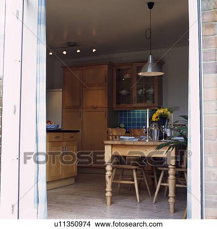 Looking through open door into kitchen with pine table and chairs View Large Photo Image Picture - Looking through open door into kitchen with pine table and chairs. Fotosearch