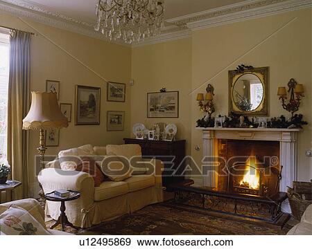 Loosecover on sofa beside fireplace in traditional living room View Large Photo Image Stock Photo - Loosecover on sofa beside fireplace in traditional living room. Fotosearch