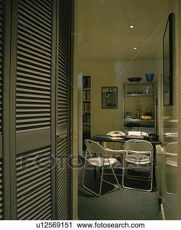 Louvre cupboard doors in sixties dining room with white chairs and black table View Large Photo Image Stock Image - Louvre cupboard doors in sixties dining room with white chairs and black table. Fotosearch