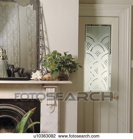 Stock Image - Marble mantlepiece and white door with engraved glass panel. Fotosearch