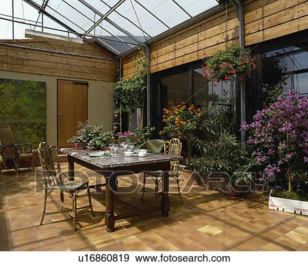 Marble topped table and cane chairs in conservatory dining room with tiled floor View Large Photo Image Stock Photo - Marble topped table and cane chairs in conservatory dining room with tiled floor. Fotosearch