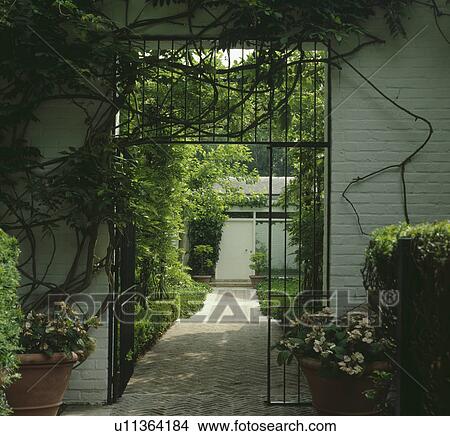 Picture - Metal gates in wall of country garden. Fotosearch