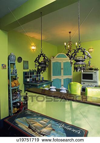 Metal lanterns suspended from ceiling in lime green kitchen with painted wooden chest in foreground View Large Photo Image Stock Photo - Metal lanterns suspended from ceiling in lime green kitchen with painted wooden chest in foreground. Fotosearch