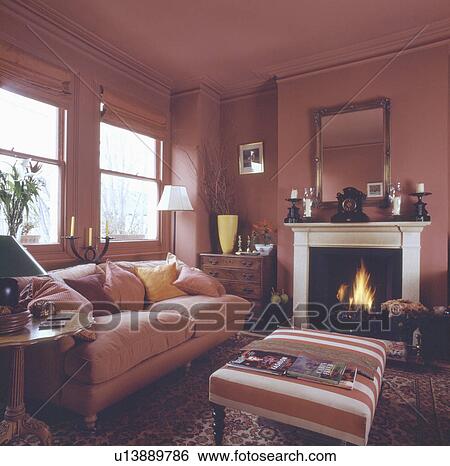 Mirror above lighted fire in fireplace in terracotta living room with striped upholstered stool and terracotta sofa View Large Photo Image Stock Photograph - Mirror above lighted fire in fireplace in terracotta living room with striped upholstered stool and terracotta sofa. Fotosearch