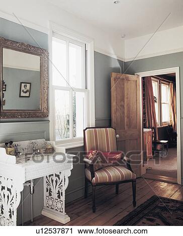 Mirror above marble basin on white wrought iron Edwardian stand in traditional bathroom with striped upholstered chair View Large Photo Image Stock Image - Mirror above marble basin on white wrought iron Edwardian stand in traditional bathroom with striped upholstered chair. Fotosearch