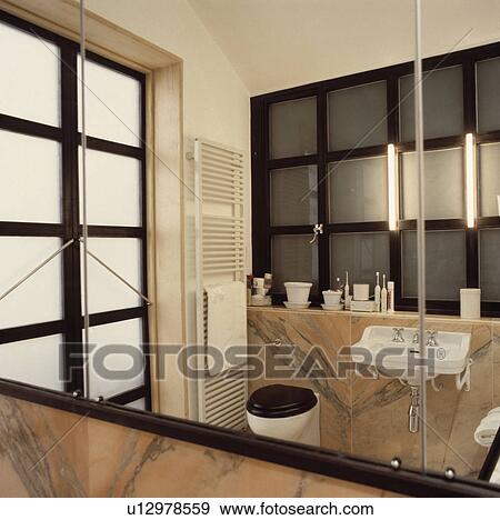 Stock Photo - Modern bathroom with basin set into pink marble unit and vertical radiator reflected in large mirror. Fotosearch