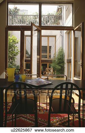 Stock Photo - Modern black table and chairs in front of glass doors in eighties dining room. Fotosearch