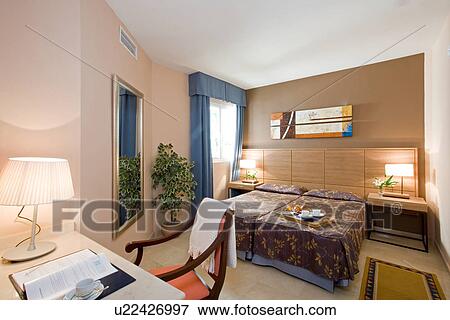 Modern hotel bedroom with lamp on desk and breakfast tray on bed View Large Photo Image Stock Photo - Modern hotel bedroom with lamp on desk and breakfast tray on bed. Fotosearch