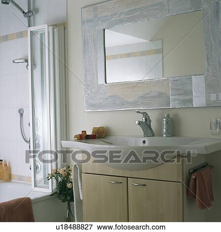 Modern mirror above built-in basin in bathroom with folding glass showerdoors on the bath View Large Photo Image Stock Photo - Modern mirror above built-in basin in bathroom with folding glass showerdoors on the bath. Fotosearch