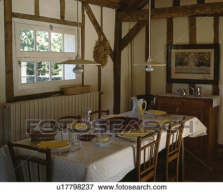 Modern pendant lights above rectangular table with plastic cloth in traditional beamed living room View Large Photo Image Stock Photo - Modern pendant lights above rectangular table with plastic cloth in traditional beamed living room. Fotosearch