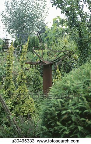 Modern rusty metal sculpture in garden with small conifer shrubs View Large Photo Image Stock Image - Modern rusty metal sculpture in garden with small conifer shrubs. Fotosearch