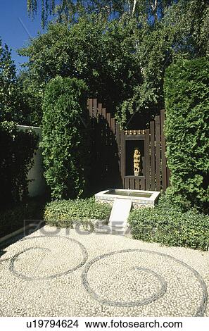 Picture - Mosaic pebble paving in front of small water feature and modern sculpture in wooden shrine. Fotosearch