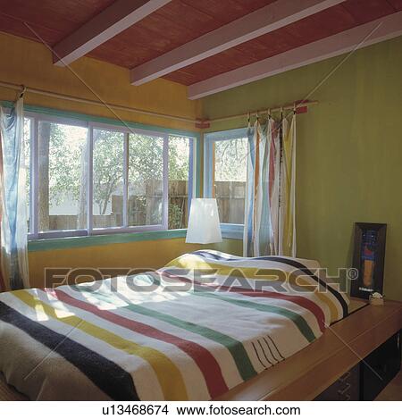 Multicoloured striped blanket on bed in yellow and green bedroom with pink and red beamed ceiling View Large Photo Image Picture - Multicoloured striped blanket on bed in yellow and green bedroom with pink and red beamed ceiling. Fotosearch