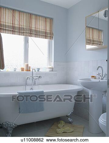 Neutral striped blind above white bath in pastel blue modern bathroom View Large Photo Image Stock Image - Neutral striped blind above white bath in pastel blue modern bathroom. Fotosearch