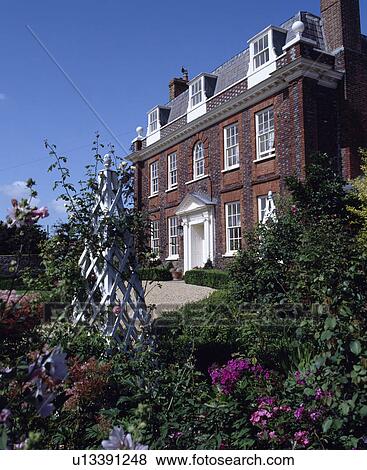 Stock Photo - Obelisk in rose border in front of large traditional Georgian country house. Fotosearch