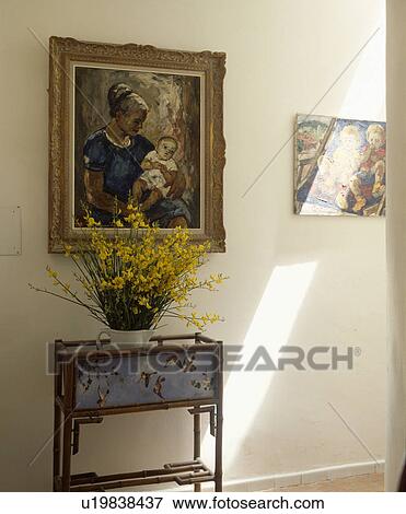 Stock Photo - Oil painting above yellow cistus in vase on decorative bamboo table in hall. Fotosearch